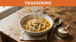Una ciotola di passatelli fumanti in brodo dorato con parmigiano e cucchiaio di legno.