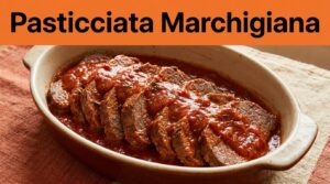Fette di manzo al pomodoro in una pirofila rustica, sotto una fascia arancione con titolo nero.
